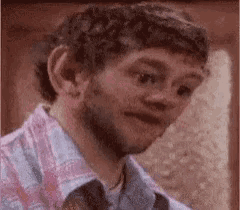a man with a beard is making a funny face while wearing a plaid shirt .