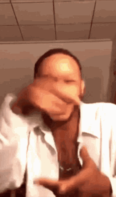 a man in a white shirt covering his mouth with his hand