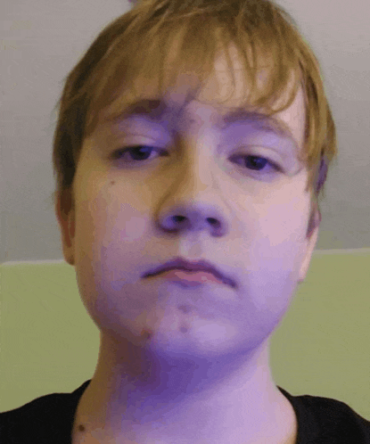 a close up of a young man 's face with a green background