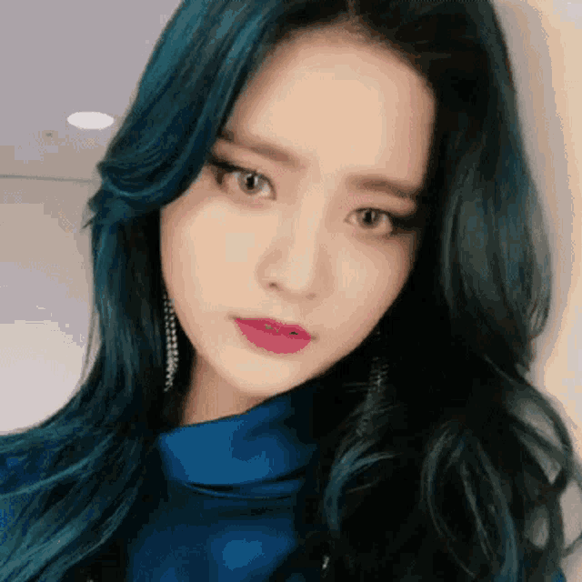 a close up of a woman 's face with blue hair and pink lips