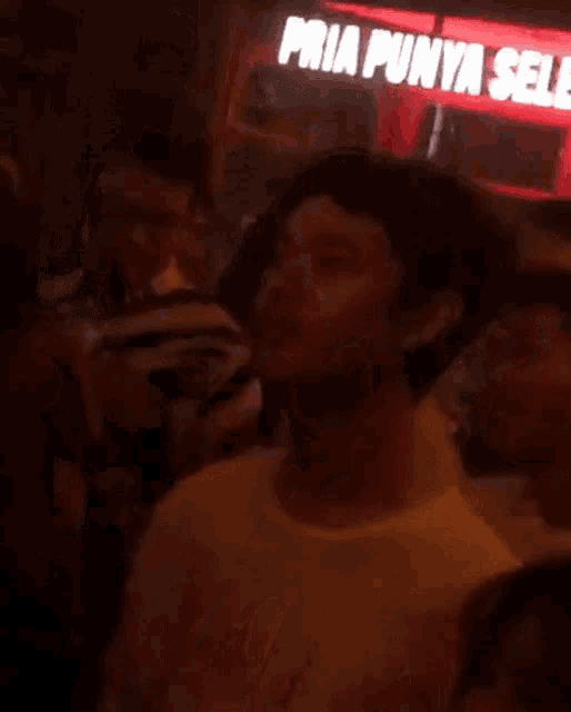 a group of people dancing in front of a sign that says pria punya seleb