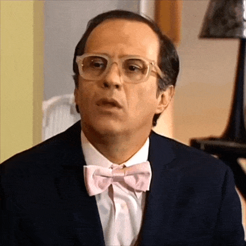 a man wearing glasses and a pink bow tie is making a funny face