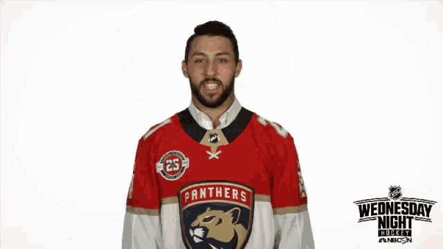 a man wearing a panthers jersey stands in front of a wednesday night hockey advertisement
