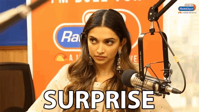 a woman is sitting in front of a microphone and the word surprise is visible