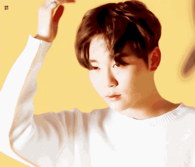 a close up of a person 's face with a yellow background and a white sweater on
