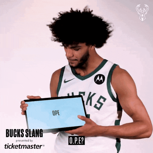 a man wearing a bucks jersey is holding a sign that says ope