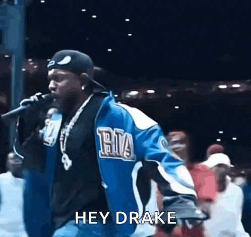 a man in a blue jacket is singing into a microphone while wearing a hat .