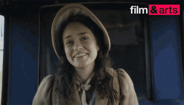 a woman wearing a hat is smiling in front of a sign that says film & arts