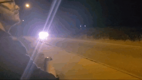 a man is driving down a road at night while holding a flashlight .