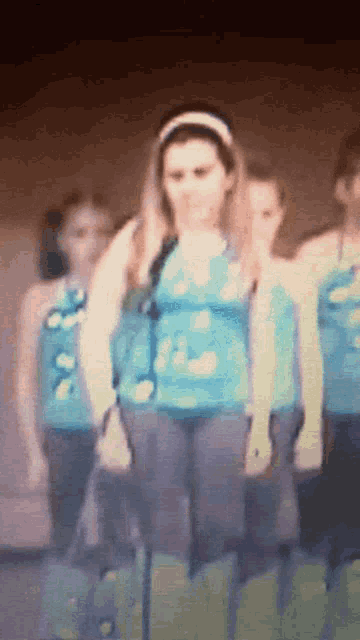 a girl in a blue shirt is standing in front of a group of other girls
