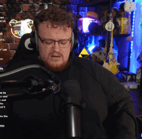 a man wearing headphones and glasses stands in front of a microphone in a room