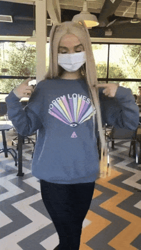 a woman wearing a mask and a sweatshirt that says ' opry loves ' on it