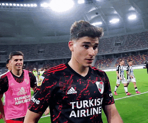 a soccer player wearing a turkish airline jersey stands on the field