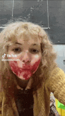 a woman with blood on her face is making a tiktok .