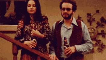 a man and a woman are standing next to each other holding bottles of beer