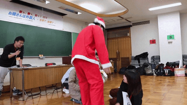 a man in a santa costume is standing in front of a sign that says ' b ' on it