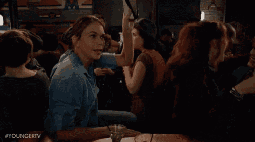 a woman is sitting at a bar with a martini in her hand and talking to a man .
