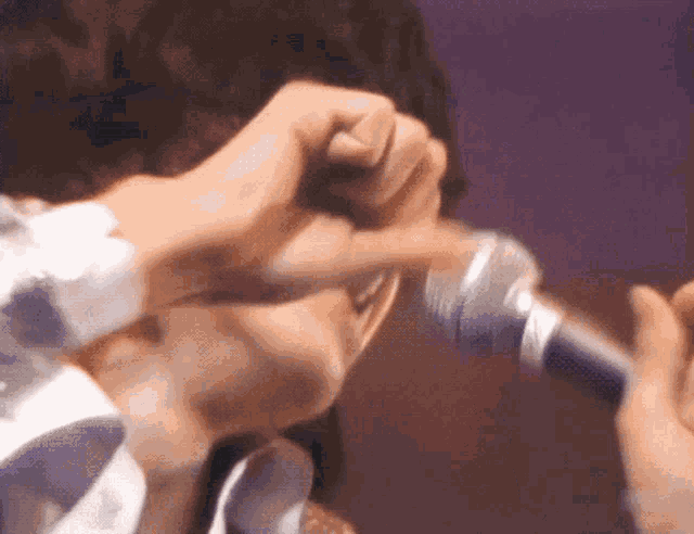 a person is singing into a microphone with a purple background