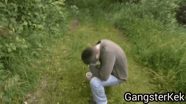 a man is kneeling down in the grass with a cup in his hand and the words gangsterkek written on the bottom