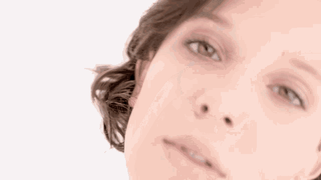 a close up of a woman 's face with a white background and a blurred background .
