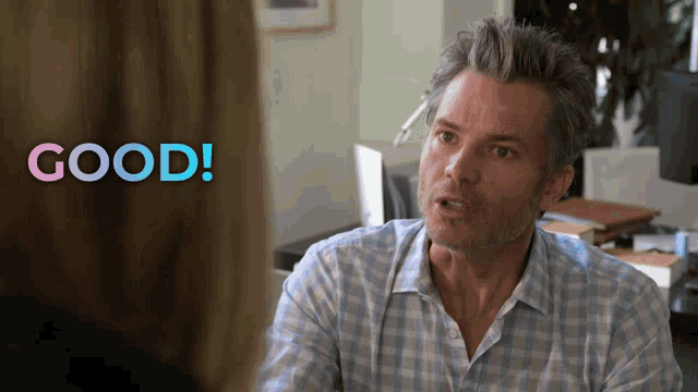 a man in a plaid shirt is talking to a woman with the words good behind him