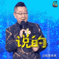 a man in a suit is holding a microphone in front of a blue background with chinese characters on it