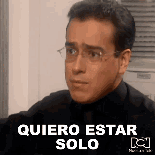 a man wearing glasses and a black shirt says " quiero estar solo " in white letters