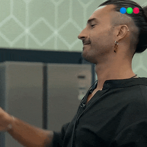 a man with a bun on his head is smiling and wearing a black shirt