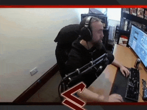 a man wearing headphones sits at a desk in front of a computer screen