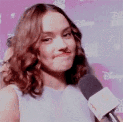 a woman is holding a microphone and making a face .