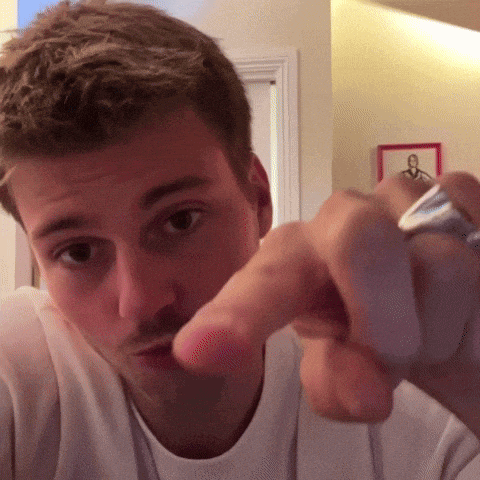 a man with a ring on his finger points at the camera