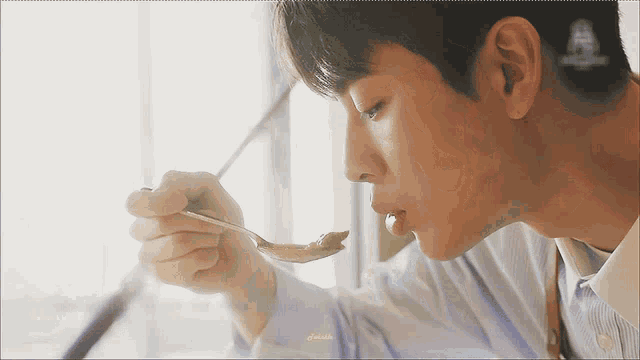 a man is eating something with a spoon in his hand