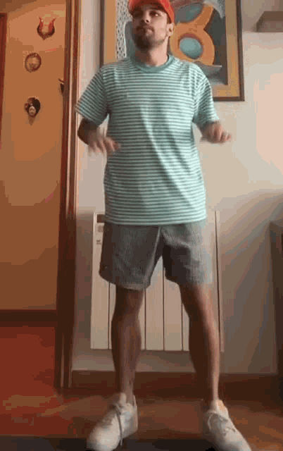 a man wearing a striped shirt and shorts is standing in a room .