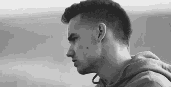 a black and white photo of a young man wearing a hoodie looking at the camera .