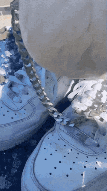 a pair of white air force 1 sneakers with a gold chain around the ankle