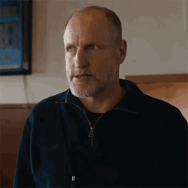 a man with a beard and a black jacket is standing in a restaurant .