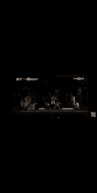 a group of dancers are performing on a stage in the dark .