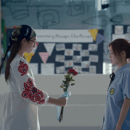 a girl in a blue shirt holds a bouquet of red roses