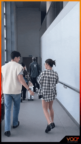 a man and a woman are walking down a hallway with the word voor on the bottom right