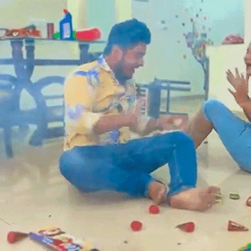 a man in a yellow shirt is sitting on the floor with a woman in blue jeans