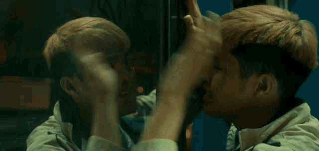 a young man is looking at his reflection in a mirror