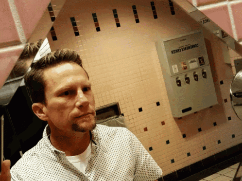 a man is looking at himself in a mirror in front of a sign that says emergency center