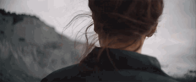 a woman 's hair is blowing in the wind behind her back