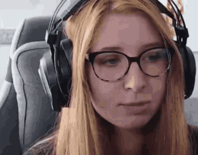 a woman with glasses and headphones is sitting in a chair .