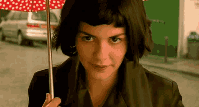 a woman is holding a red polka dot umbrella