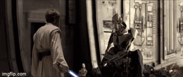a man in a robe is standing next to a robot with a lightsaber .