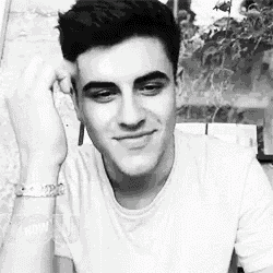 a black and white photo of a young man wearing a white shirt and a bracelet .