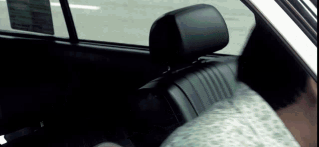 a person is sitting in the back seat of a car with a sticker on the window that says ' warning '