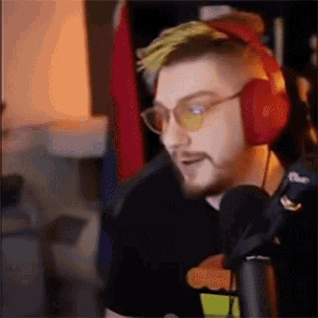 a man with a beard wearing headphones and sunglasses is talking into a microphone .