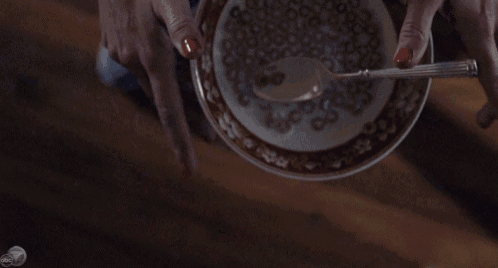 a woman 's hand is reaching for a broken glass on a table